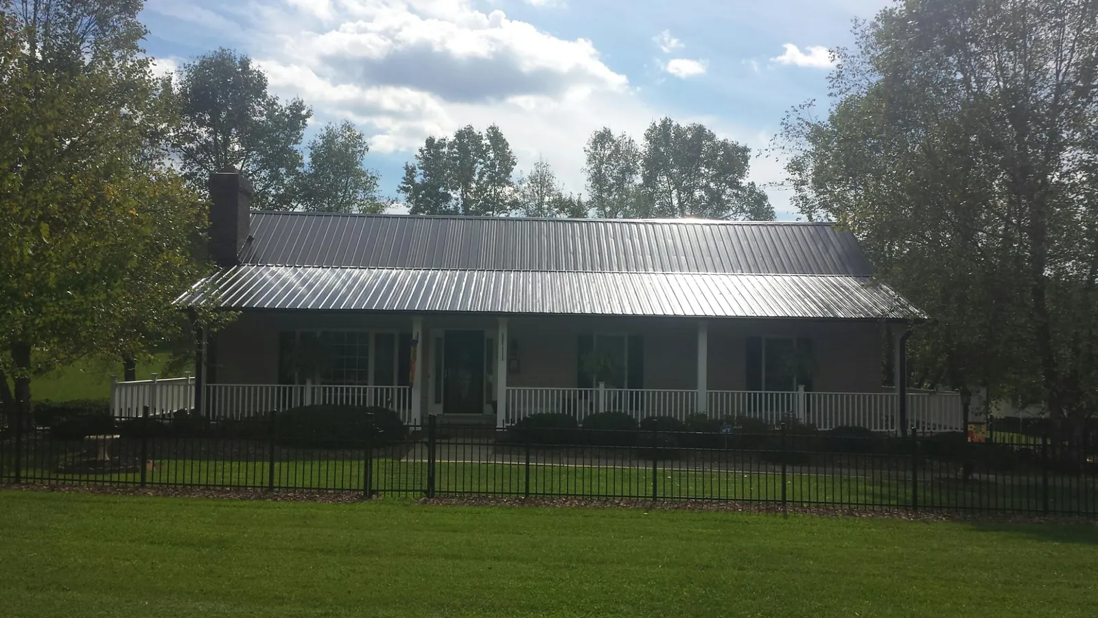 Gray metal roof on a brick ranch with a full width front porch — Gutter Guard Installation work by our crew in Gladstone