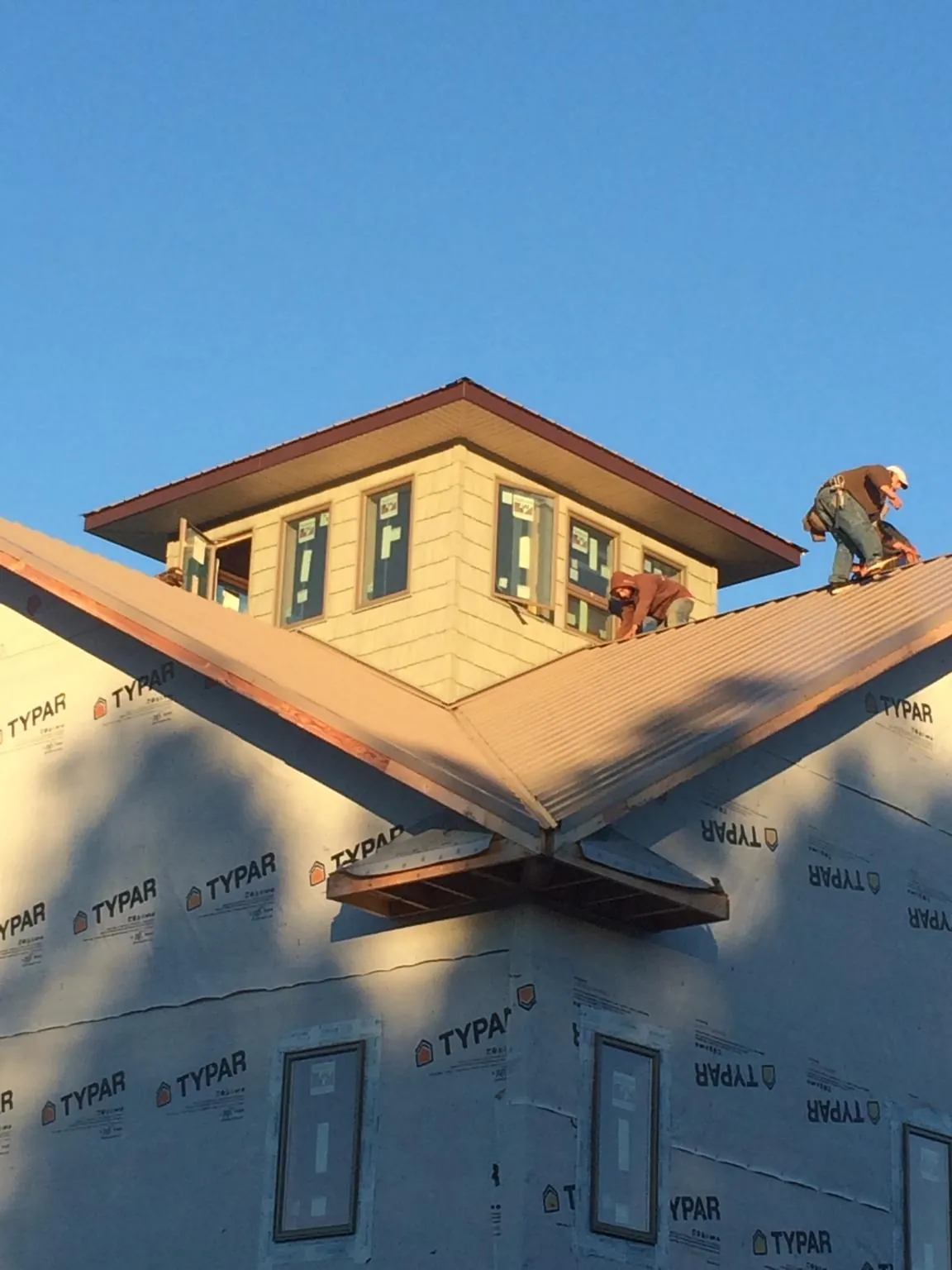 Roofers working around a rooftop cupola on a new metal roof at sunset — Roof Waterproofing in Gladstone by Roofing Brothers